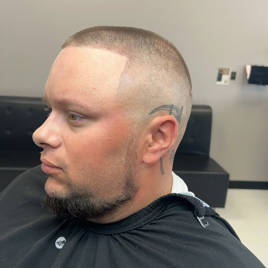 Close fade with curved hair design and beard, shown in full side profile
